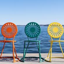 orange, green and yellow chairs sitting alongside shore of Lake Mendota