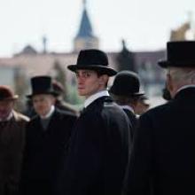 Still from film Franz (2025), men in black bowler hats stand in a crowd.