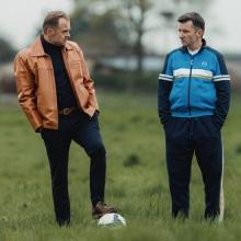 Still from film Sparrow (2024), two men stand on soccer field.