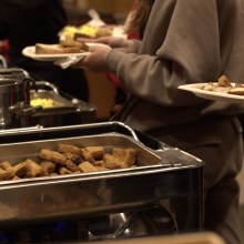 A buffet line featuring a tray of warm sausage and eggs