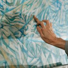 Hand working on a blue pastel drawing.