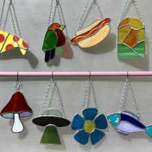 Selection of suncatchers in various shapes, including a pizza, a hot dog and a mushroom.