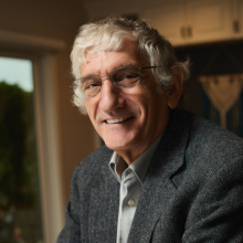  A headshot of John Martinis wearing a button down and grey blazer. 
