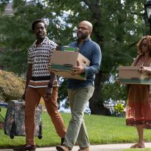 Still from film American Fiction, three people carrying moving supplies walk down the sidewalk.