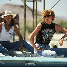Still from film Thelma & Louise, two women sit in a car in the desert.