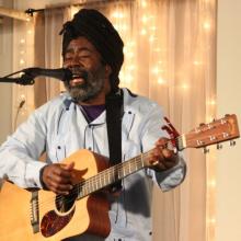 Mona Augustin performing with an acoustic guitar. 