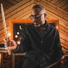 Photo of Nate Smith holding a drum stick. 