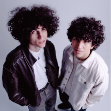 Zohar and Adam in front of a light gray backrop.