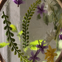 A photo of pressed flowers in a sun catcher. 