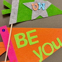 Photo of two pennants made from felt with the words "Be You" and "UW". 