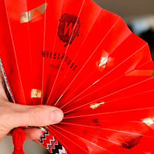 Photo of someone holding a red folding fan. 
