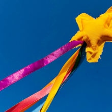 Photo of a wand with a star attached with several colored ribbons in the sky. 