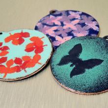 Photo of three different enamel pendants. 