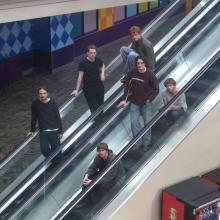 The six-piece band Dutch Interior poses for a photo on 2 escalators.