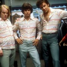 Three men wearing striped shirts posing next to a mannequin. 