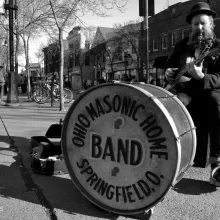 Boo Mullarky busking with a large drum and resonator guitar.