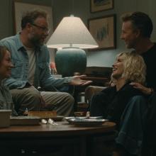 four people sit in a living room laughing and talking